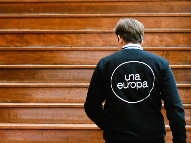 Male staff member walking up stairs wearing an Una Europa sweater